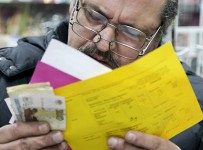 Мужчина заполняет квитанции на оплату коммунальных услуг